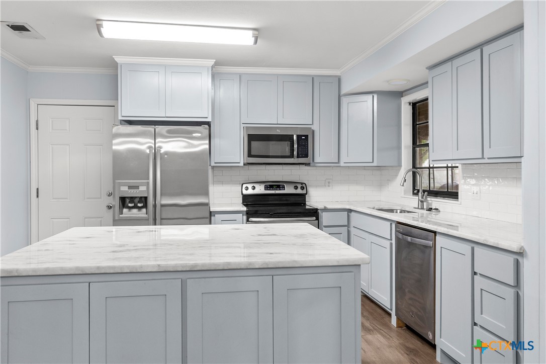 204 Berwick Road Victoria, TX 77904 - Photo 12 of 38 a kitchen with granite countertop a refrigerator and a stove top oven