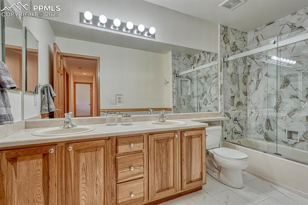 339 Sandreed Place Colorado Springs, CO 80921 - Photo 30 of 50 Bathroom with double vanity and shower / bath combination with glass door