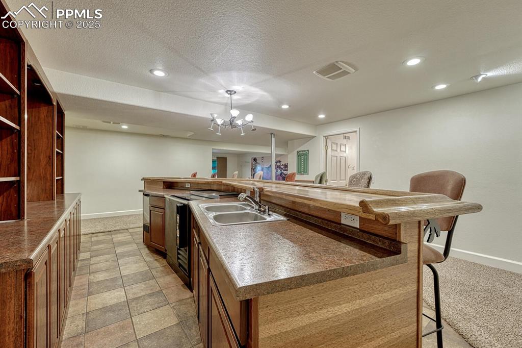 339 Sandreed Place Colorado Springs, CO 80921 - Photo 38 of 50 Kitchen with a kitchen breakfast bar, a large island with sink, recessed lighting, a textured ceiling, and light carpet