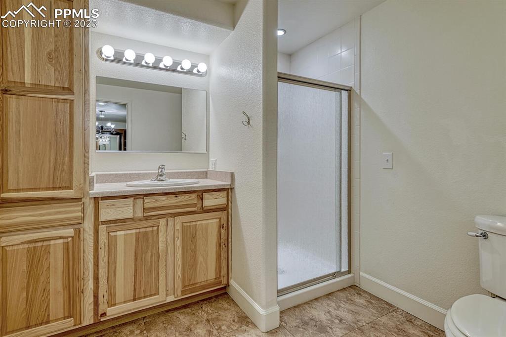 339 Sandreed Place Colorado Springs, CO 80921 - Photo 39 of 50 Bathroom with a textured wall, a stall shower, vanity, and light tile patterned floors