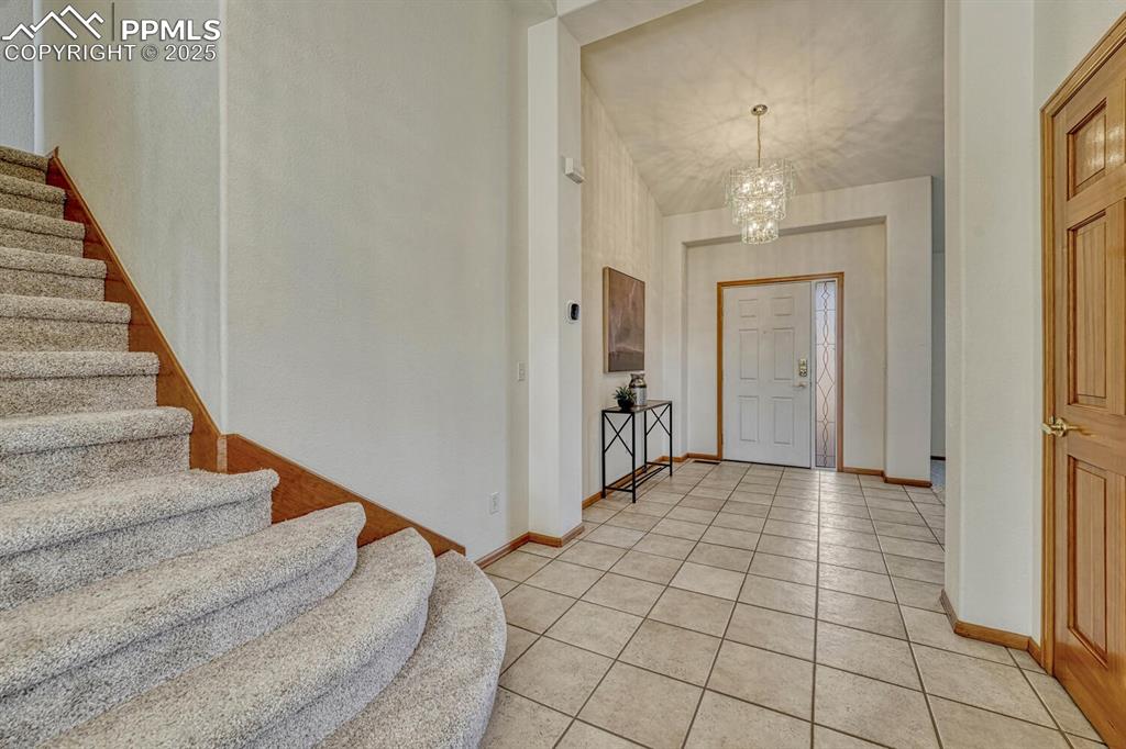 339 Sandreed Place Colorado Springs, CO 80921 - Photo 4 of 50 Entrance foyer featuring light tile patterned flooring, a chandelier, and stairway