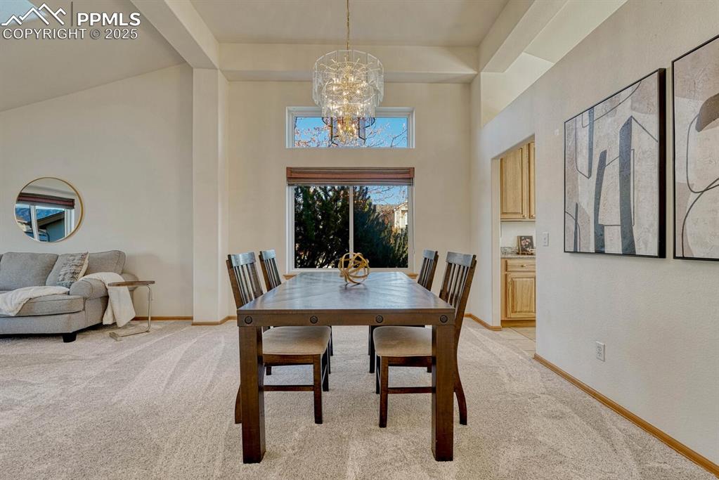 339 Sandreed Place Colorado Springs, CO 80921 - Photo 9 of 50 Dining space with light colored carpet, beam ceiling, a high ceiling, and a chandelier
