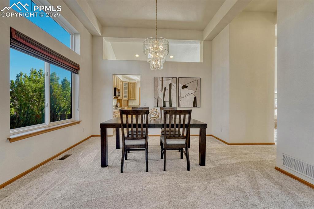 339 Sandreed Place Colorado Springs, CO 80921 - Photo 10 of 50 Dining area featuring light colored carpet, a chandelier, and a high ceiling