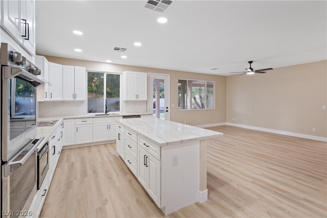 1662 Ravanusa Drive Henderson, NV 89052 - Photo 12 of 74 A well-lit, open-concept kitchen features a large center island and modern appliances, flowing into an inviting living area.