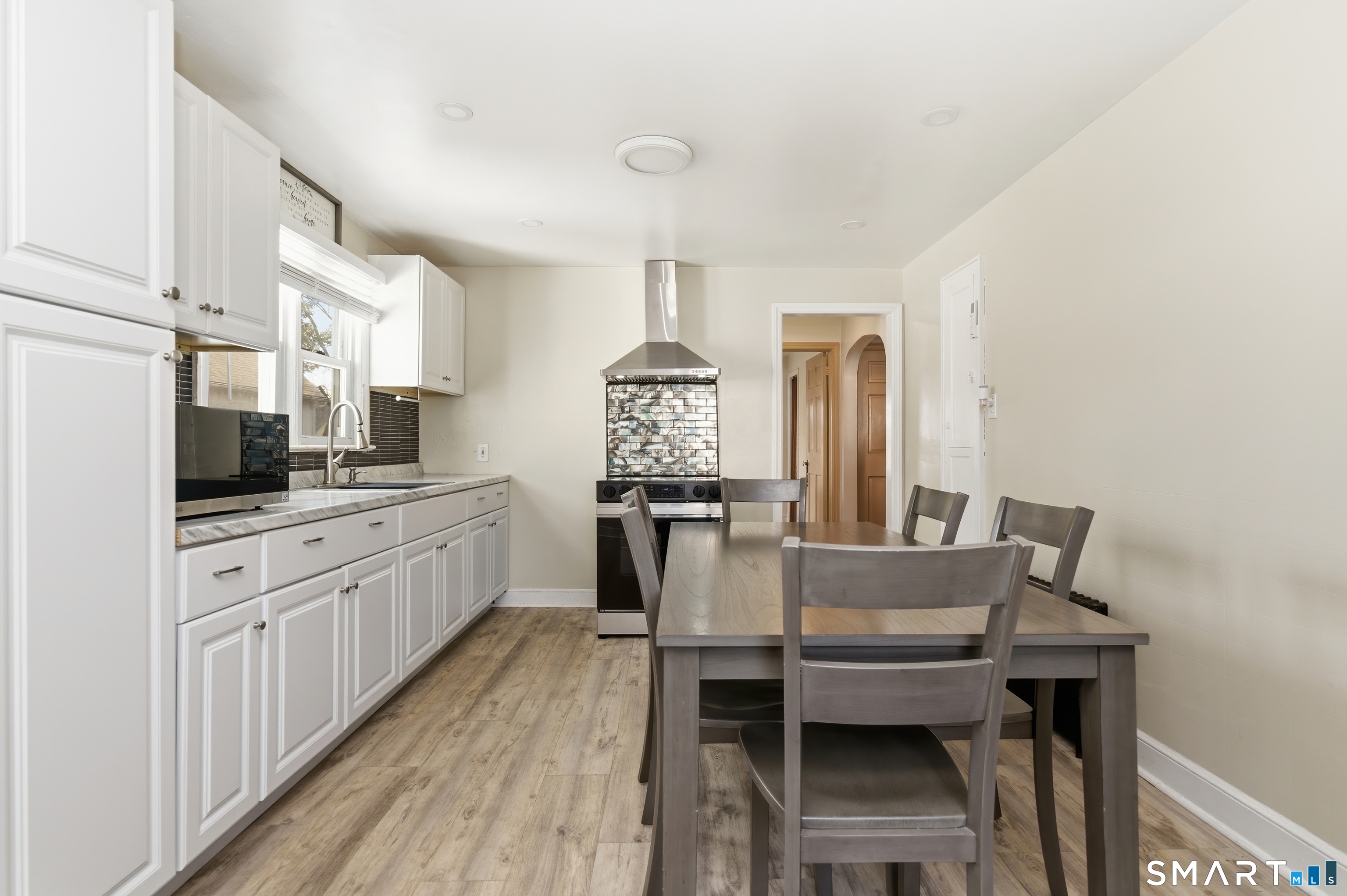 170 Hillside Avenue Bridgeport, CT 06604 - Photo 6 of 35 a kitchen with granite countertop a dining table chairs and white cabinets