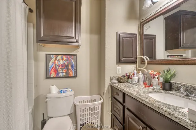 a bathroom with a granite countertop toilet sink and mirror