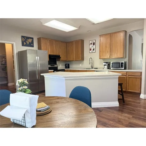 a kitchen with kitchen island a stove a sink a refrigerator dining table and chairs