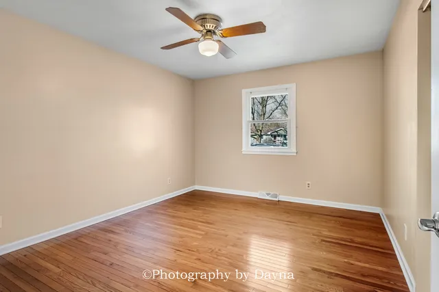an empty room with wooden floor and a ceiling fan
