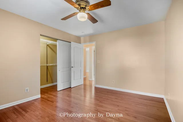 an empty room with wooden floor closet and ceiling fan