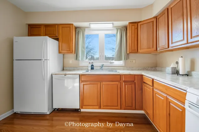 a kitchen with stainless steel appliances granite countertop a refrigerator a sink and dishwasher with wooden cabinets