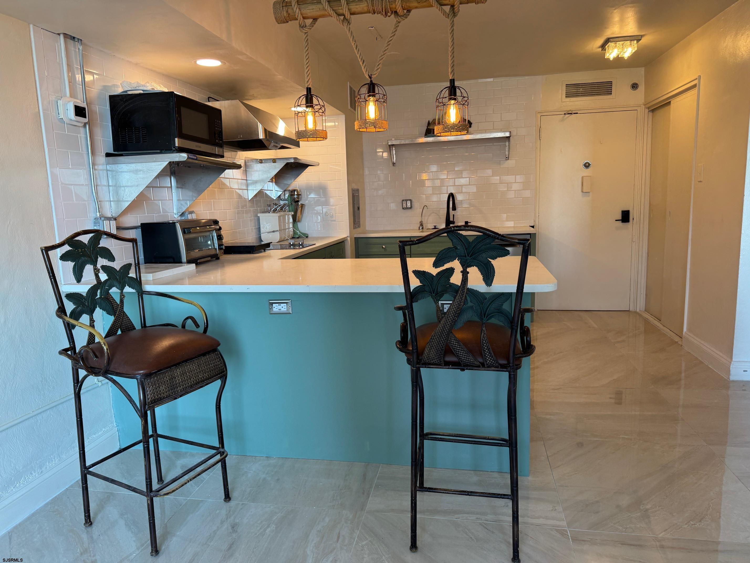 101 South Raleigh Avenue, Unit 210 Atlantic City, NJ 08401 - Photo 8 of 24 a kitchen with stainless steel appliances kitchen island granite countertop dining table chairs and a wooden floor
