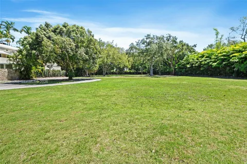 a big yard with lots of green space and trees in the background