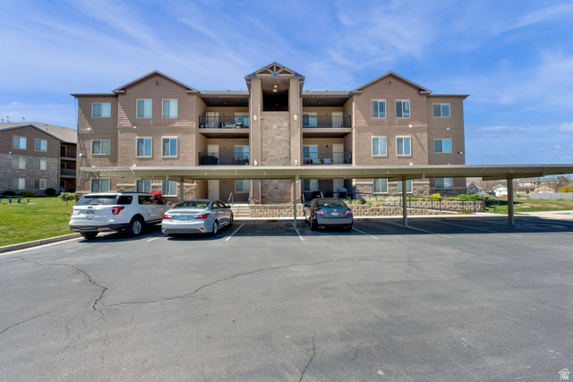 Multi-story building featuring stone and siding facade, multiple private balconies, and covered parking