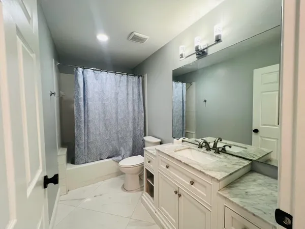 a bathroom with a granite countertop sink a toilet a mirror and shower