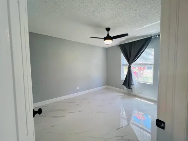 an empty room with ceiling fan and windows