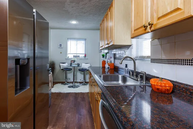 a kitchen with stainless steel appliances granite countertop a sink a stove and a wooden floor