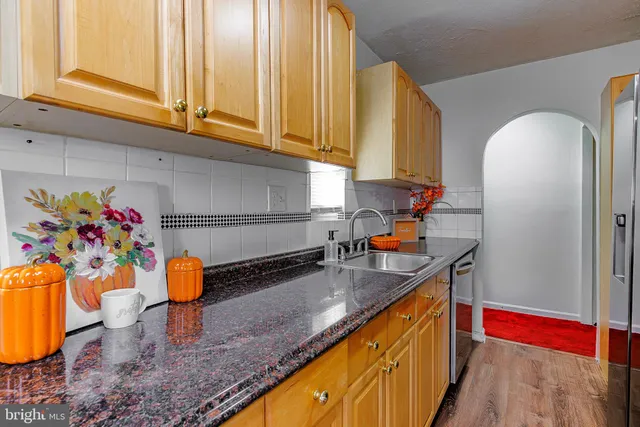 a kitchen with stainless steel appliances granite countertop a sink a stove and a wooden cabinets