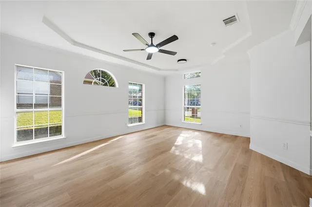 a view of an empty room with a window and wooden floor