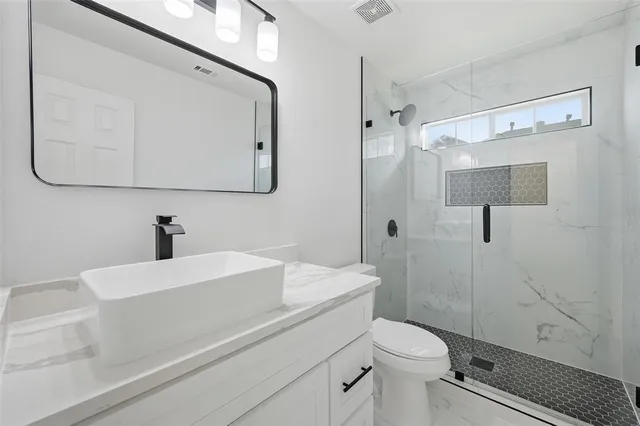 a bathroom with a sink a toilet and shower