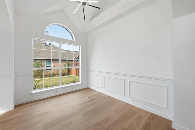 an empty room with wooden floor cabinet and windows