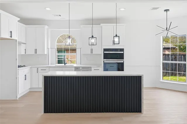 a kitchen with stainless steel appliances granite countertop a sink a stove a refrigerator and island with wooden floor