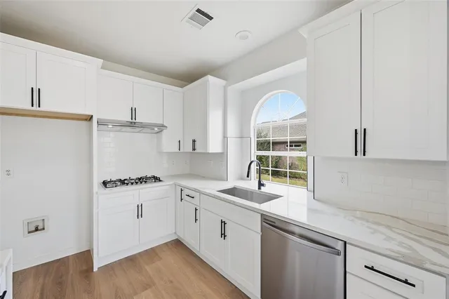 a kitchen with a white cabinets and wooden floor
