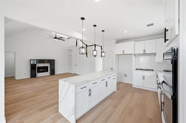 a large kitchen with stainless steel appliances granite countertop a stove oven and a refrigerator