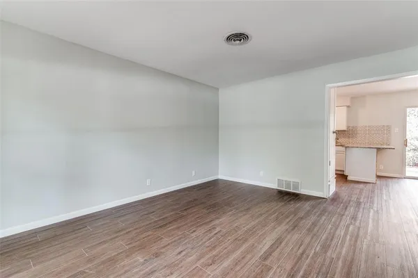 a view of empty room with wooden floor and a window