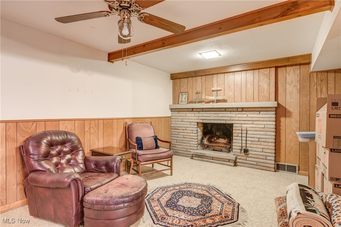 4712 Hillside Road Independence, OH 44131 - Photo 29 of 47 Living area with wood walls, beam ceiling, a wainscoted wall, a fireplace with raised hearth, and ceiling fan