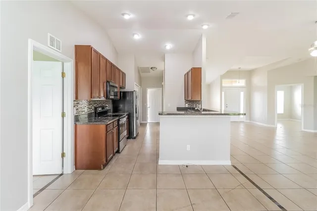 a view of a kitchen with kitchen island granite countertop a refrigerator a stove a sink and a oven