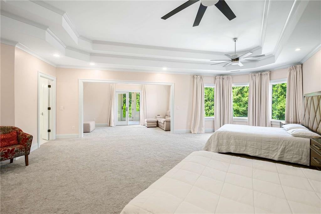 2340 Thisel Down Drive Statham, GA 30666 - Photo 59 of 105 a spacious bedroom with a large bed and a chandelier fan