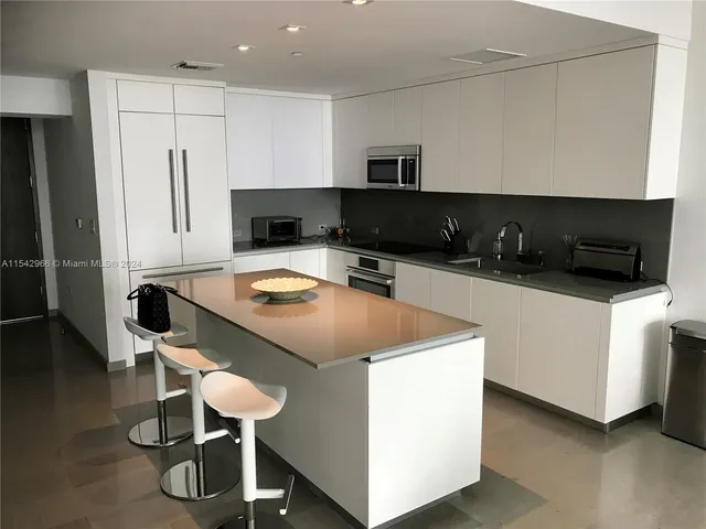 a kitchen with a sink a microwave a refrigerator and chairs