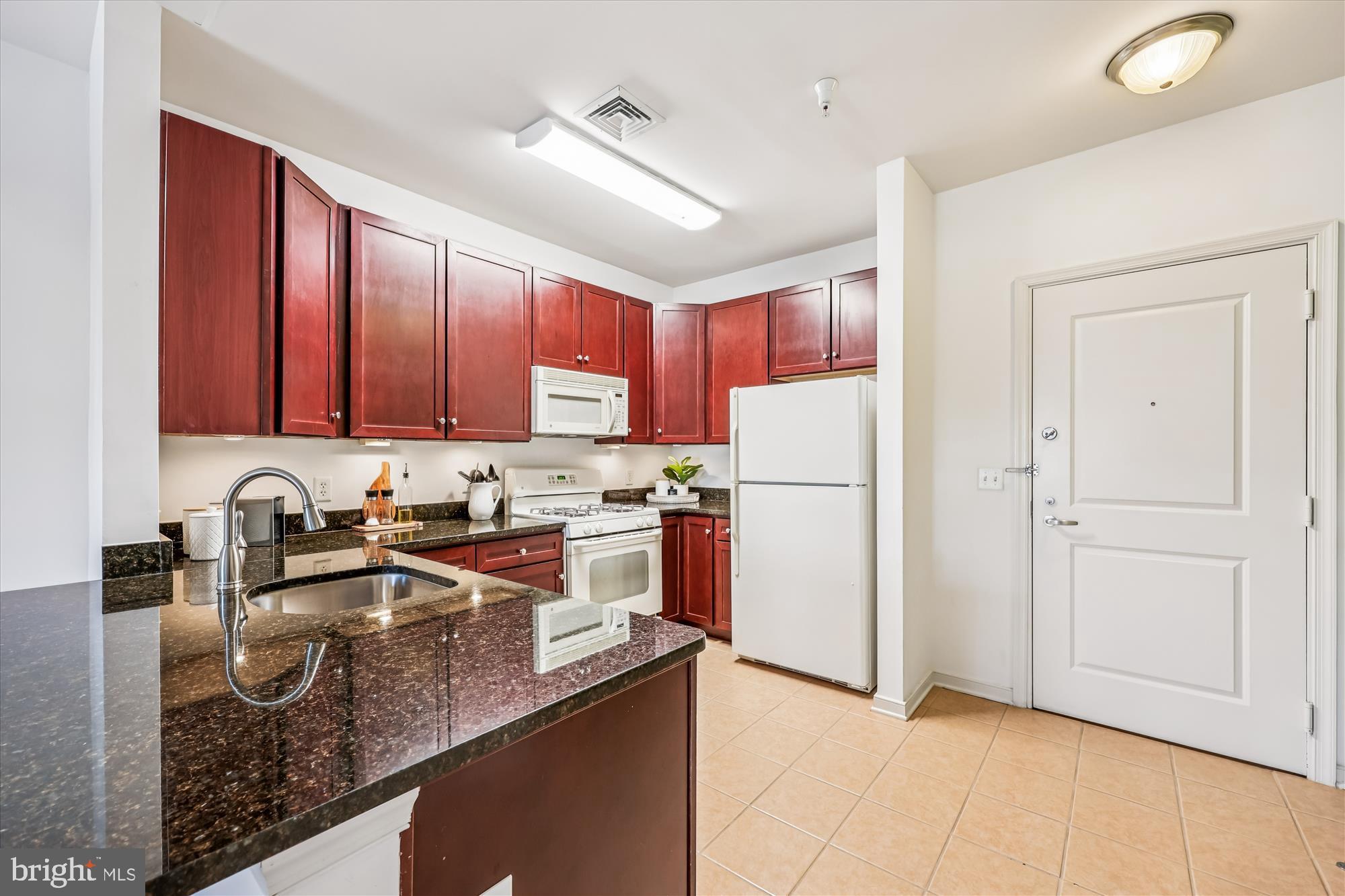 8045 Newell Street, Unit 215 Silver Spring, MD 20910 - Photo 12 of 31 a kitchen with stainless steel appliances granite countertop a refrigerator a sink dishwasher a stove with wooden cabinets and floor