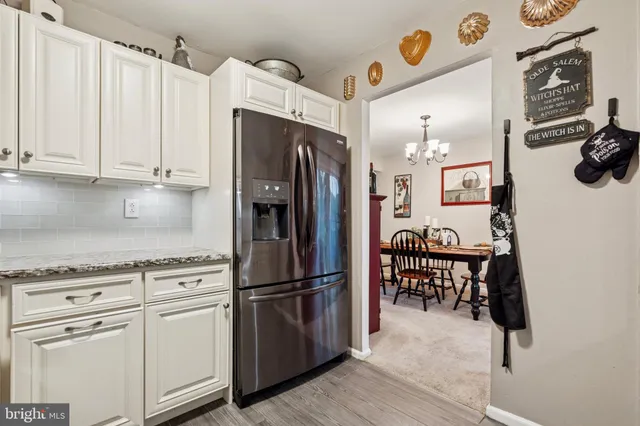 a kitchen with stainless steel appliances granite countertop a refrigerator sink and white cabinets