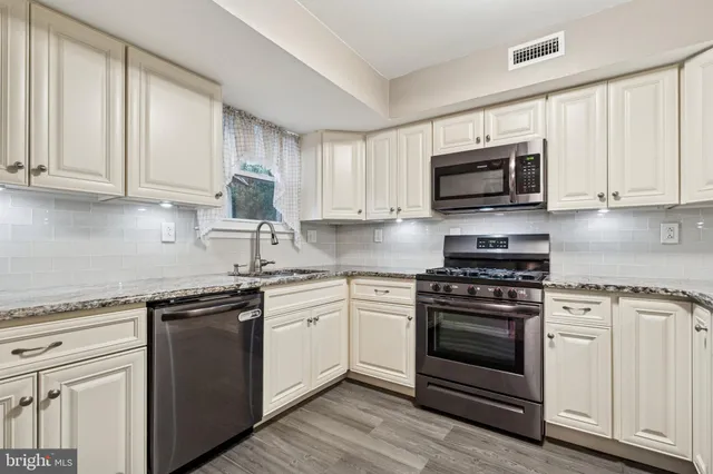 a kitchen with granite countertop white cabinets and stainless steel appliances