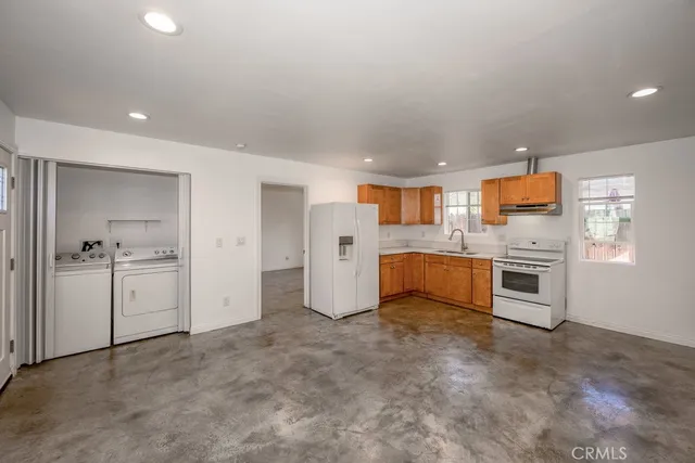 a large white kitchen with stainless steel appliances granite countertop a stove and a refrigerator