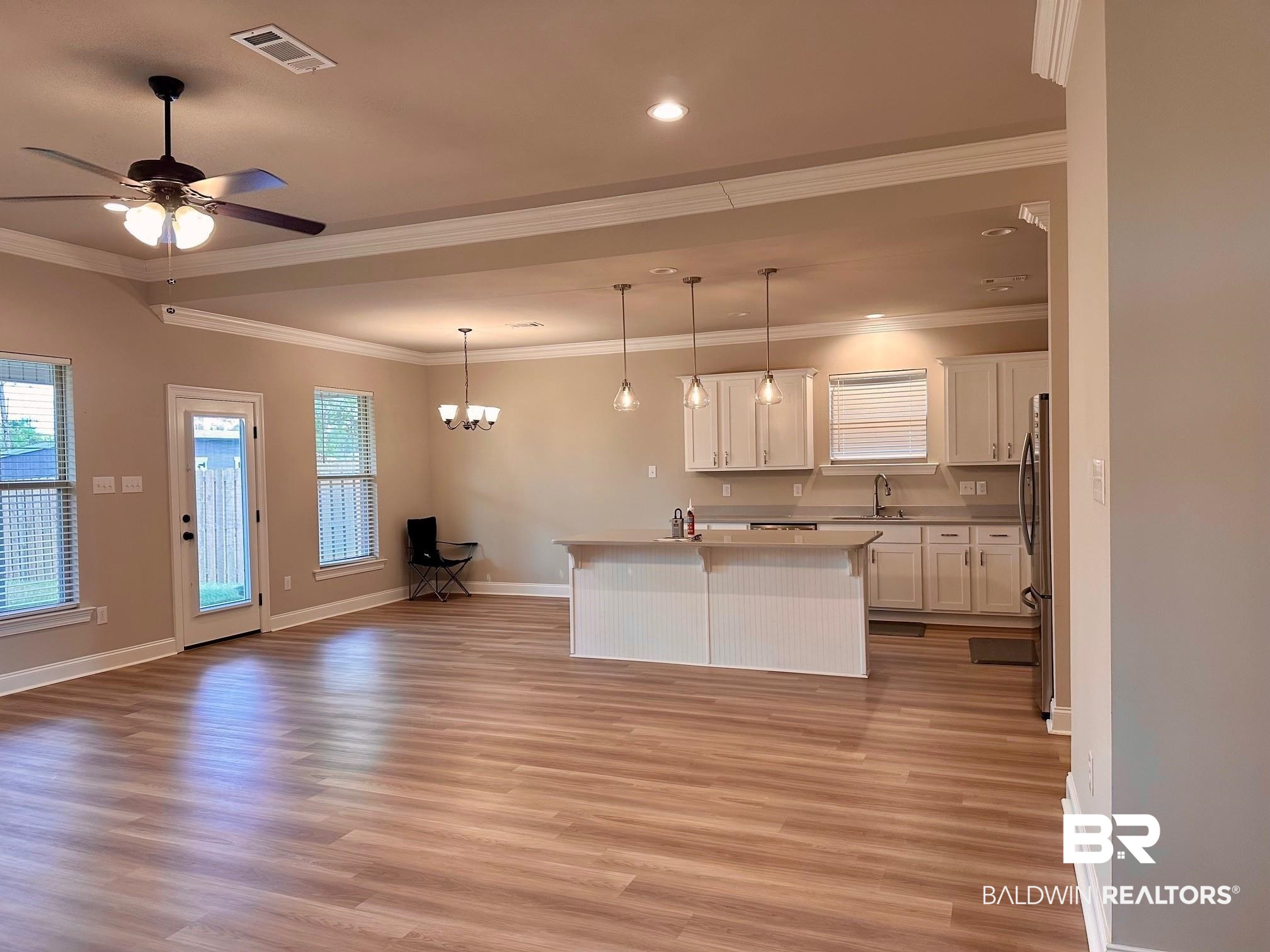 1009 Ruisseau Drive Foley, AL 36535 - Photo 16 of 55 Kitchen featuring sink, a kitchen island, white cabinetry, light hardwood / wood-style floors, and pendant lighting
