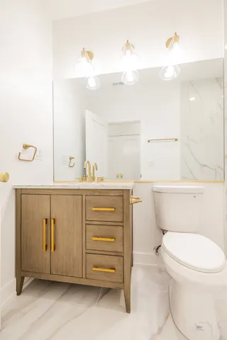 a bathroom with a toilet a sink a mirror and vanity