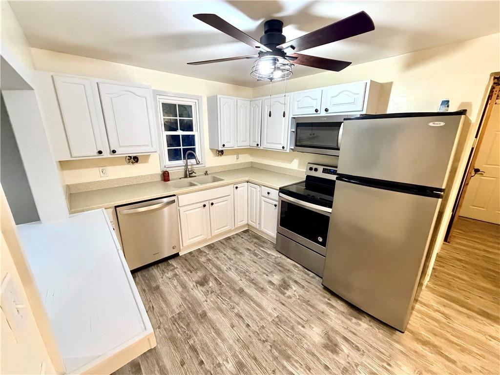 166 Jr Street Hopwood, PA 15445 - Photo 6 of 23 a kitchen with stainless steel appliances granite countertop a refrigerator a stove a sink and white cabinets with wooden floor