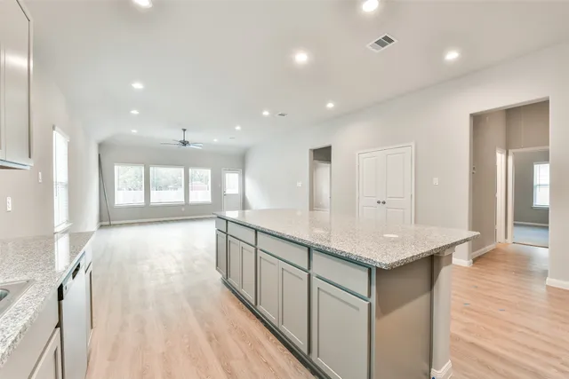 a large kitchen with stainless steel appliances granite countertop a large counter top a sink and a refrigerator