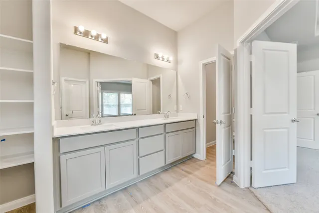 a spacious bathroom with a double vanity sink a mirror and a shower