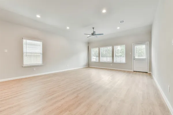an empty room with wooden floor and windows