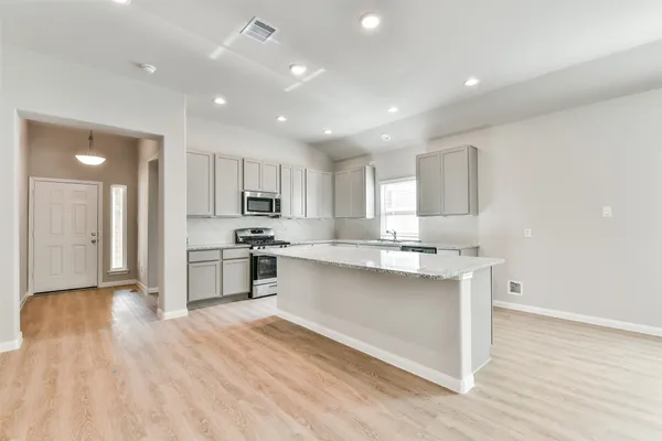 a kitchen with stainless steel appliances granite countertop a sink a stove a refrigerator and cabinets