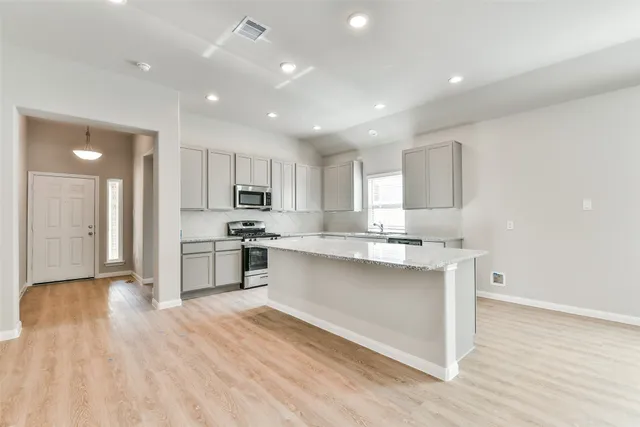 a kitchen with stainless steel appliances granite countertop a sink a stove a refrigerator and cabinets