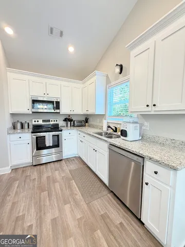 a kitchen with granite countertop a sink cabinets stainless steel appliances and a counter space