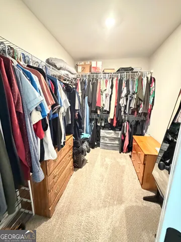 a view of walk in closet with clothes and shoes