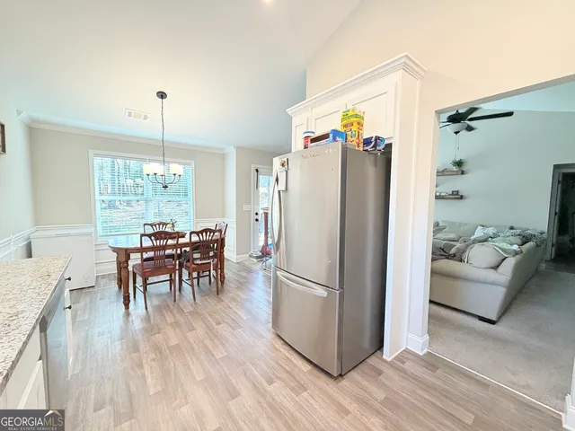 a kitchen with stainless steel appliances granite countertop a refrigerator and a dining table view