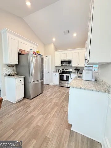 a kitchen with granite countertop a refrigerator stove top oven and sink