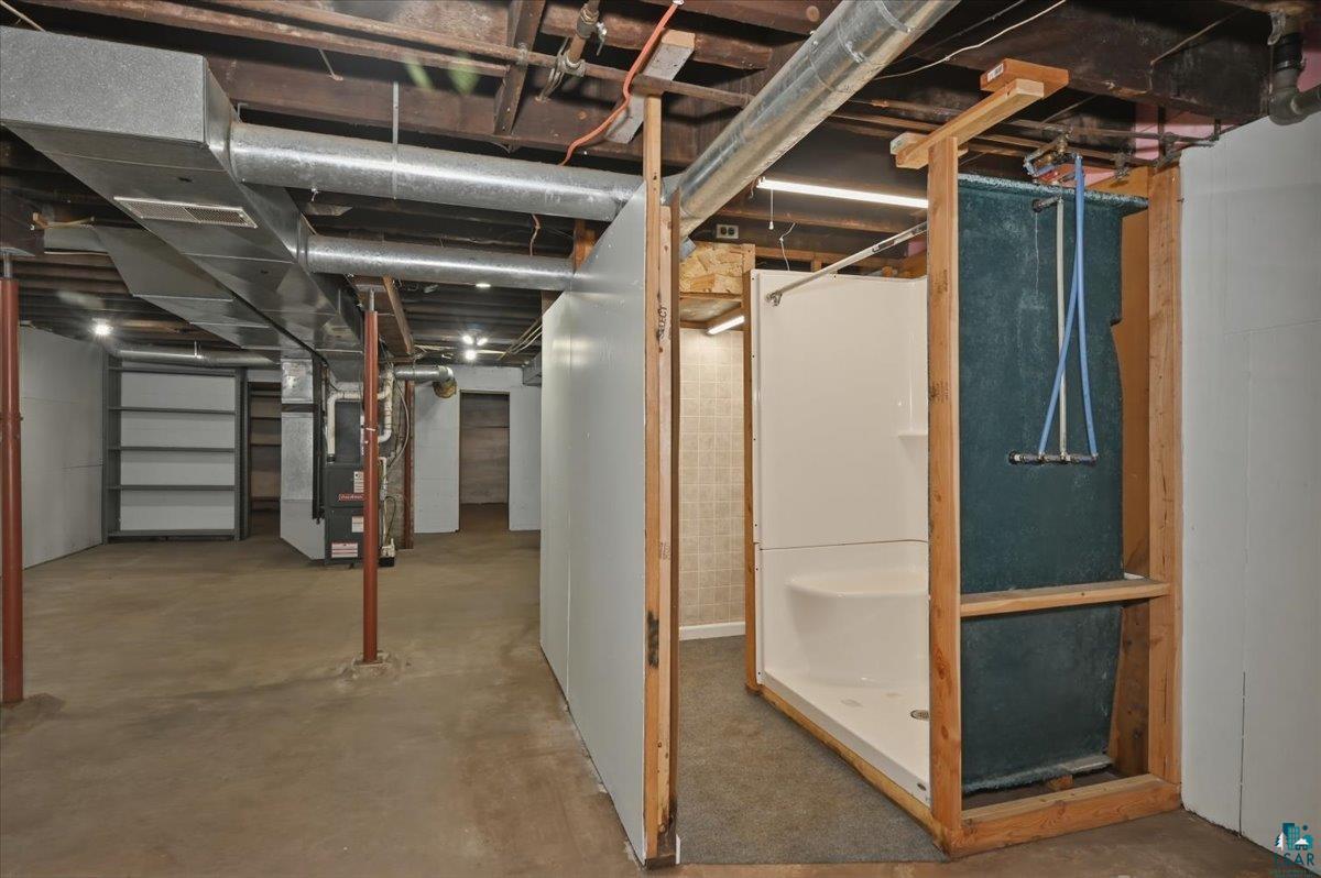 5319 East 3rd Street Superior, WI 54880 - Photo 22 of 33 Unfinished basement featuring a pre-fabricated shower unit with visible plumbing, exposed overhead ductwork, concrete flooring, and storage shelving