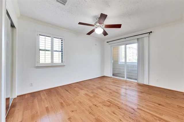a view of empty room with wooden floor and fan